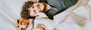 Un hombre y su perro acostados juntos en una cama